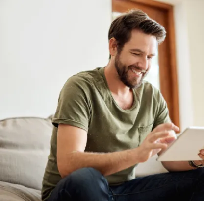 Un homme dans un canapé regarde une tablette